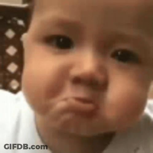 A Baby Is Making A Funny Face While Looking At The Camera . GIF