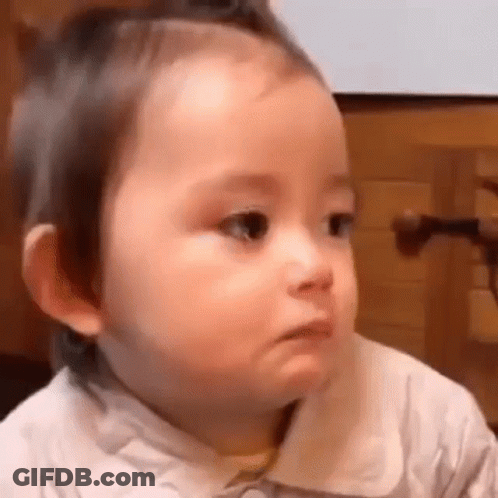 A Baby Is Making A Funny Face While Sitting Down . GIF