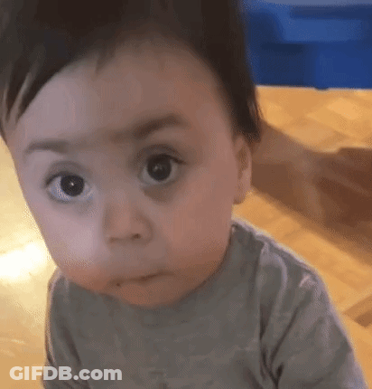 A Baby Is Making A Funny Face While Sitting On The Floor . GIF