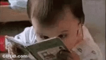 A Baby Is Reading A Book With His Eyes Closed And His Mouth Open . GIF
