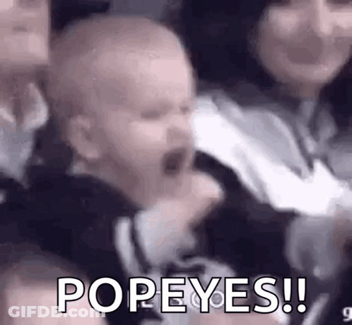 A Baby Is Screaming In A Crowd While Being Held By A Woman And A Man . GIF