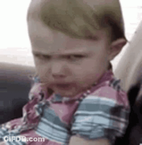 A Baby Is Sitting In A Car Seat And Making An Angry Face . GIF