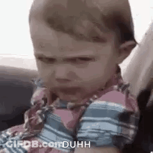 A Baby Is Sitting In A Car Seat With A Funny Face . GIF