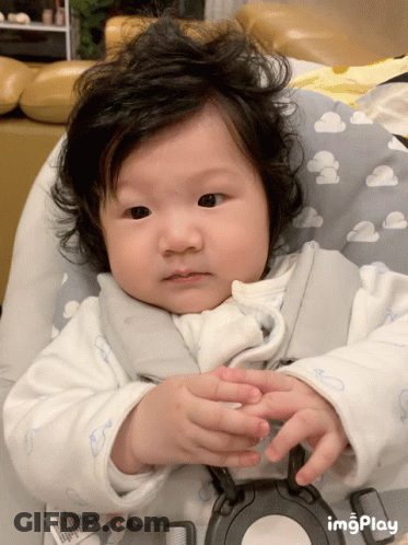 A Baby Is Sitting In A High Chair With A Cloudy Pillow GIF