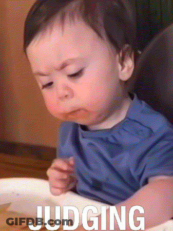 A Baby Is Sitting In A High Chair With The Word Judging Written On His Arm GIF