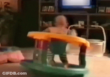 A Baby Is Sitting In A Rocking Chair In Front Of A Tv GIF