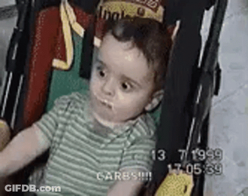 A Baby Is Sitting In A Stroller With A Crown On His Head . GIF