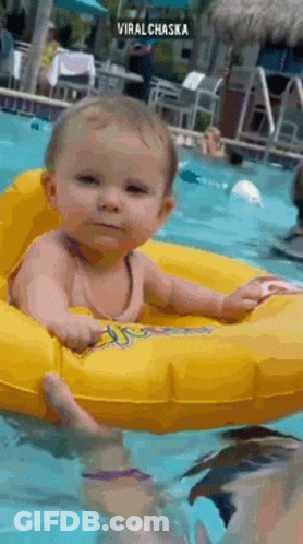 A Baby Is Sitting In An Inflatable Ring In A Swimming Pool . GIF