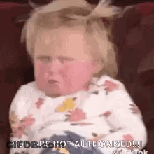 A Baby Is Sitting On A Couch And Making A Face . GIF