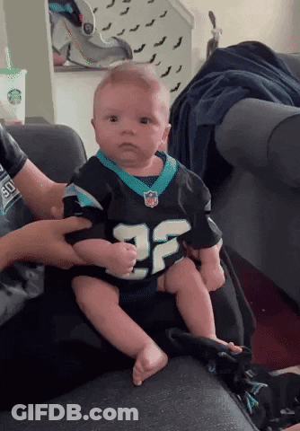A Baby Is Sitting On A Couch Wearing A Number 25 Jersey GIF