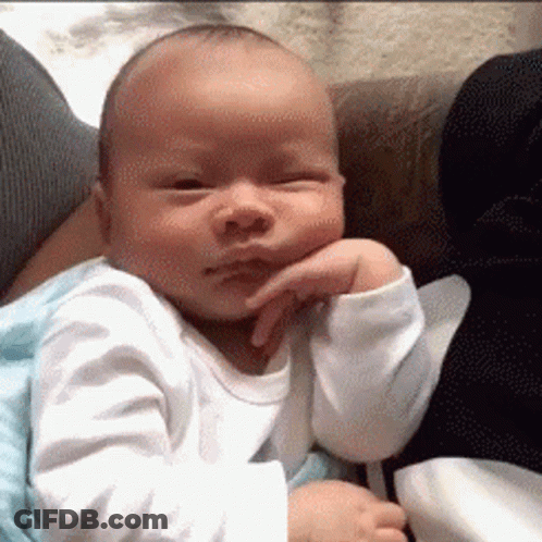 A Baby Is Sitting On A Couch With His Hand On His Face . GIF