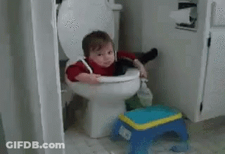 A Baby Is Sitting On A Toilet With A Broom In His Hand . GIF