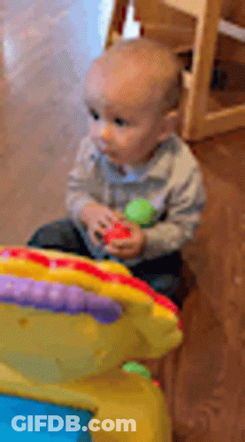 A Baby Is Sitting On The Floor Playing With A Toy GIF