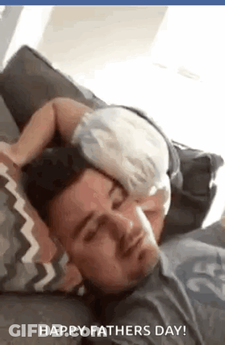 A Baby Is Sleeping On A Man 'S Head On A Couch . GIF