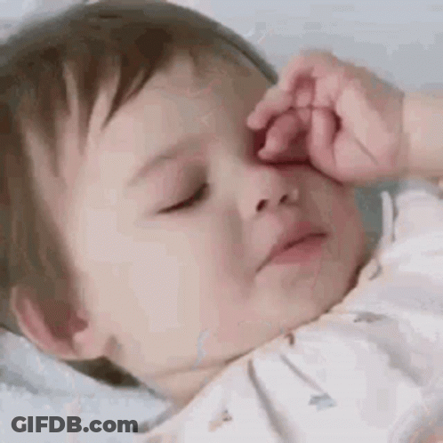 A Baby Is Sleeping With His Eyes Closed And Rubbing His Nose . GIF