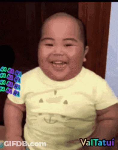 A Baby Is Smiling And Wearing A Yellow Shirt With A Cat Face On It GIF
