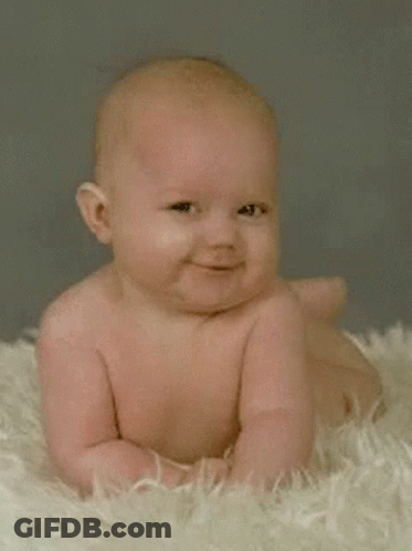 A Baby Is Smiling While Laying On A Fluffy Blanket GIF