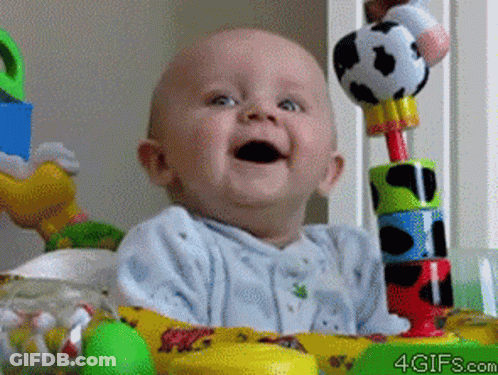 A Baby Is Smiling While Sitting In A Crib With Toys And The Website 4Gifs.com Is Visible In The Corner GIF