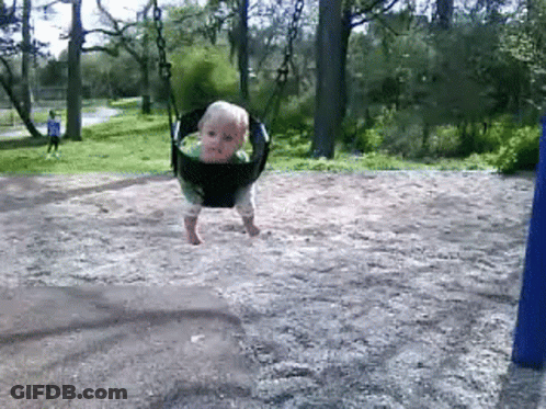 A Baby Is Swinging On A Swing Set In The Dirt GIF