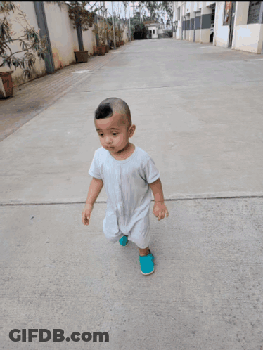 A Baby Is Walking On A Sidewalk With A Manhole Cover In The Background GIF