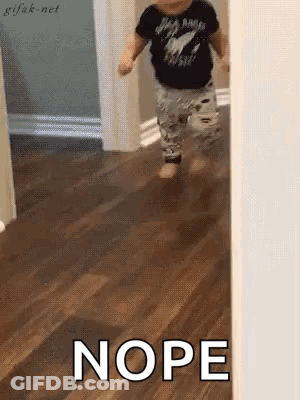 A Baby Is Walking On A Wooden Floor And The Word Nope Is Written On The Floor . GIF