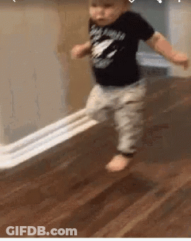 A Baby Is Walking On A Wooden Floor With A Piece Of Toilet Paper . GIF