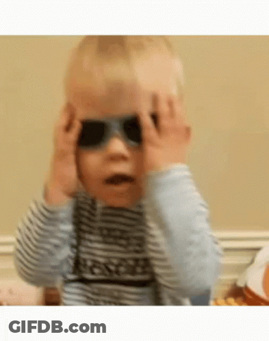 A Baby Is Wearing Sunglasses And Covering His Eyes . GIF