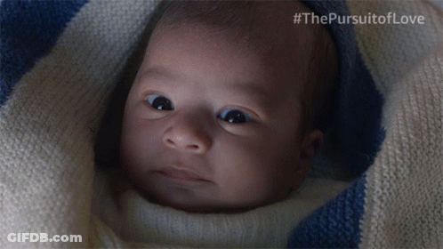A Baby Is Wrapped In A Blue And White Striped Blanket With #Thepursuitoflove Written On The Bottom GIF
