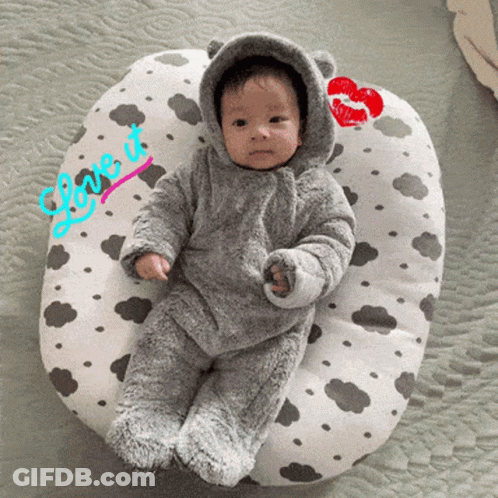 A Baby Laying On A Pillow That Says Love It On It GIF
