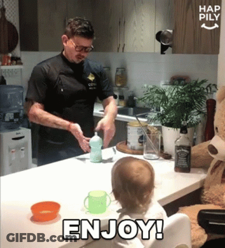 A Baby Sitting At A Table With A Bottle Of Jack Daniel 'S In The Background GIF