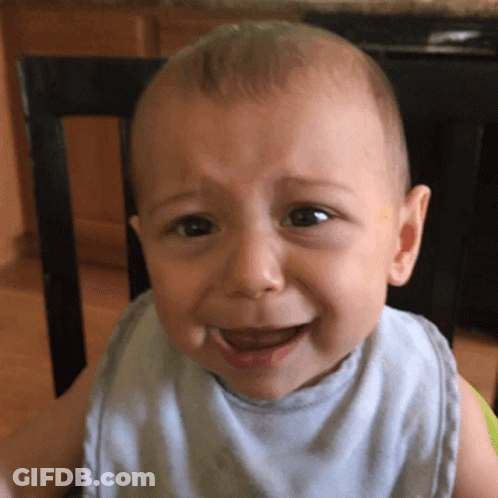 A Baby Wearing A Bib Is Crying While Sitting In A Chair GIF