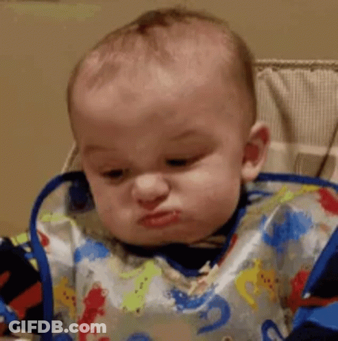 A Baby Wearing A Bib Is Sitting In A High Chair And Making A Funny Face . GIF