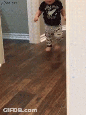 A Baby Wearing A Black Shirt That Says Rock N Roll Is Running On A Wooden Floor . GIF