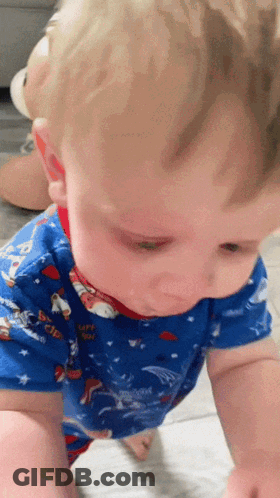A Baby Wearing A Blue Shirt With Paw Patrol On It Is Crawling On The Floor GIF