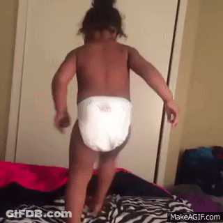 A Baby Wearing A Diaper Is Dancing On A Bed . GIF
