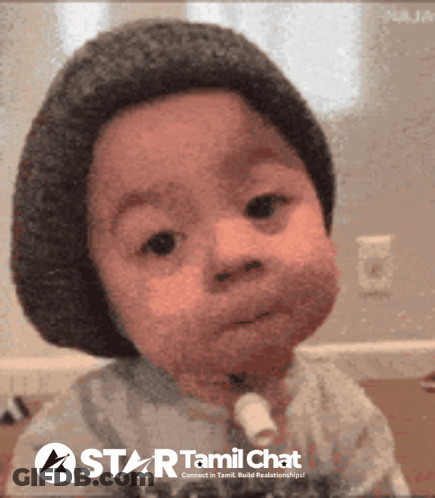 A Baby Wearing A Hat And A Star Tamil Chat Logo Behind Him GIF