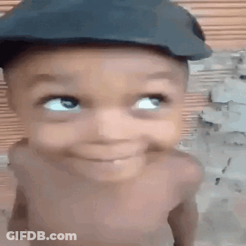 A Baby Wearing A Hat Is Smiling And Looking Up . GIF