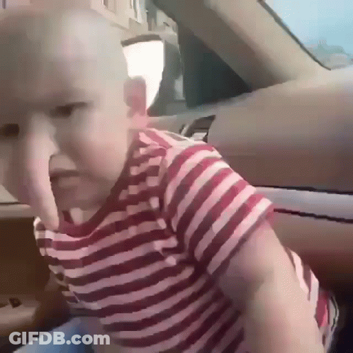 A Baby Wearing A Red And White Striped Shirt Is Sitting In The Back Seat Of A Car GIF