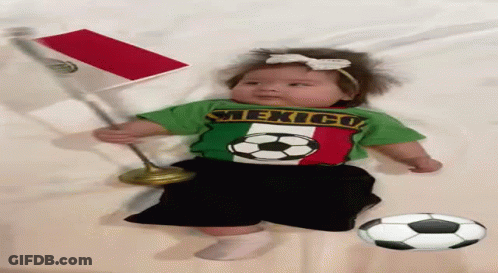 A Baby Wearing A Shirt That Says Mexico Is Laying On A Bed GIF