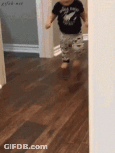 A Baby Wearing A Shirt That Says Rock N Roll Is Walking On A Wood Floor GIF