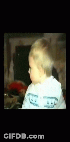 A Baby Wearing A White Sweater With A Smiley Face On It GIF
