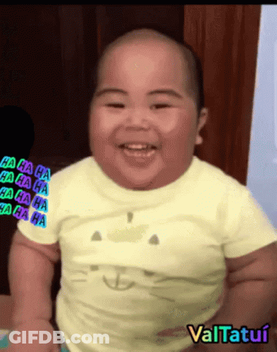 A Baby Wearing A Yellow Shirt With A Cat On It Smiles GIF