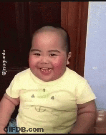A Baby Wearing A Yellow Shirt With An Apple On It Smiles GIF