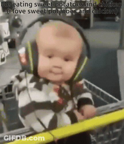 A Baby Wearing Headphones Is Sitting In A Shopping Cart And Eating Sweet Potatoes And Chicken . GIF