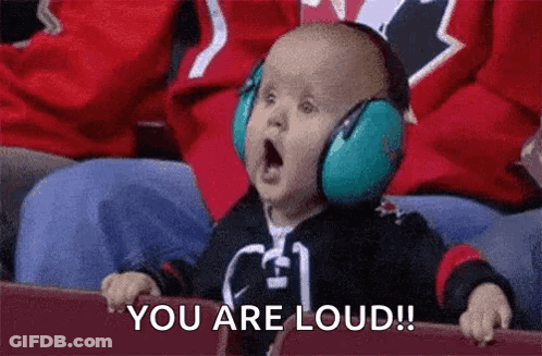 A Baby Wearing Headphones Is Sitting In A Stadium And Saying `` You Are Loud ! '' GIF