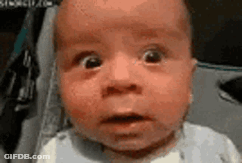 A Baby With A Surprised Look On His Face Is Sitting In A Car Seat . GIF