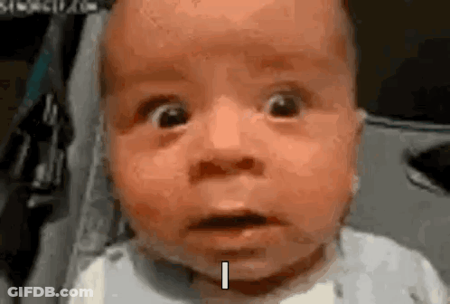 A Baby With A Surprised Look On His Face Is Sitting In A Stroller And Making A Funny Face . GIF