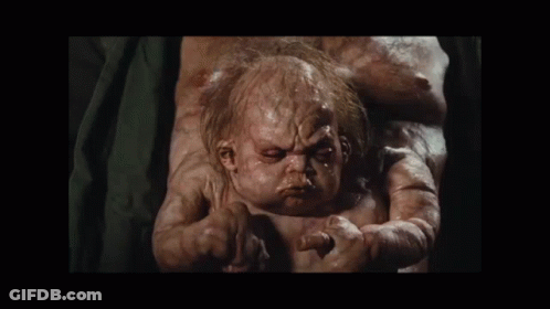 A Baby With A Very Ugly Face Is Being Held By A Woman GIF