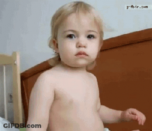 A Baby Without A Shirt Is Standing In Front Of A Bed With The Website Gfbir.com Visible In The Corner GIF