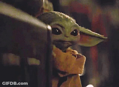 A Baby Yoda From Star Wars Is Sitting On A Fence Looking At The Camera . GIF